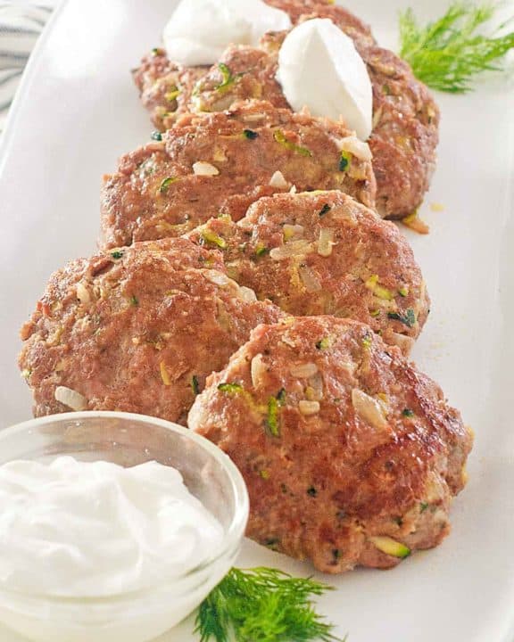 pan-fried chicken croquettes and sour cream on a platter.