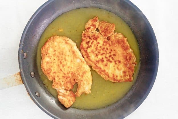 cooking lemon chicken in a skillet.