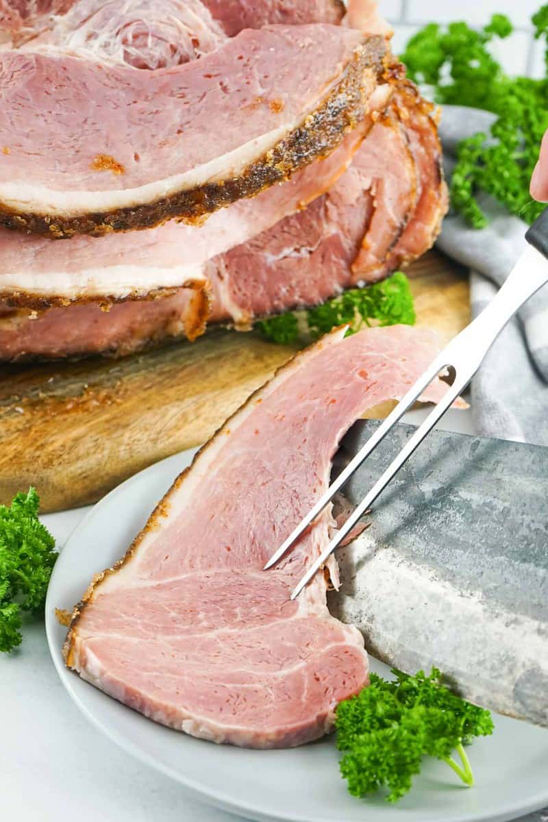 a slice of homemade honey baked ham in front of the ham.