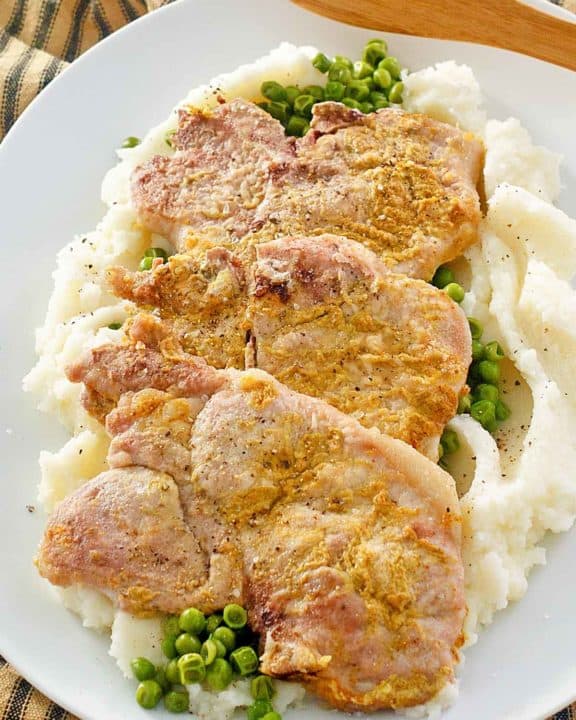 mustard pork chops over peas and mashed potatoes.