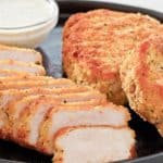 pork milanese and a small bowl of lemon caper sauce on a platter.