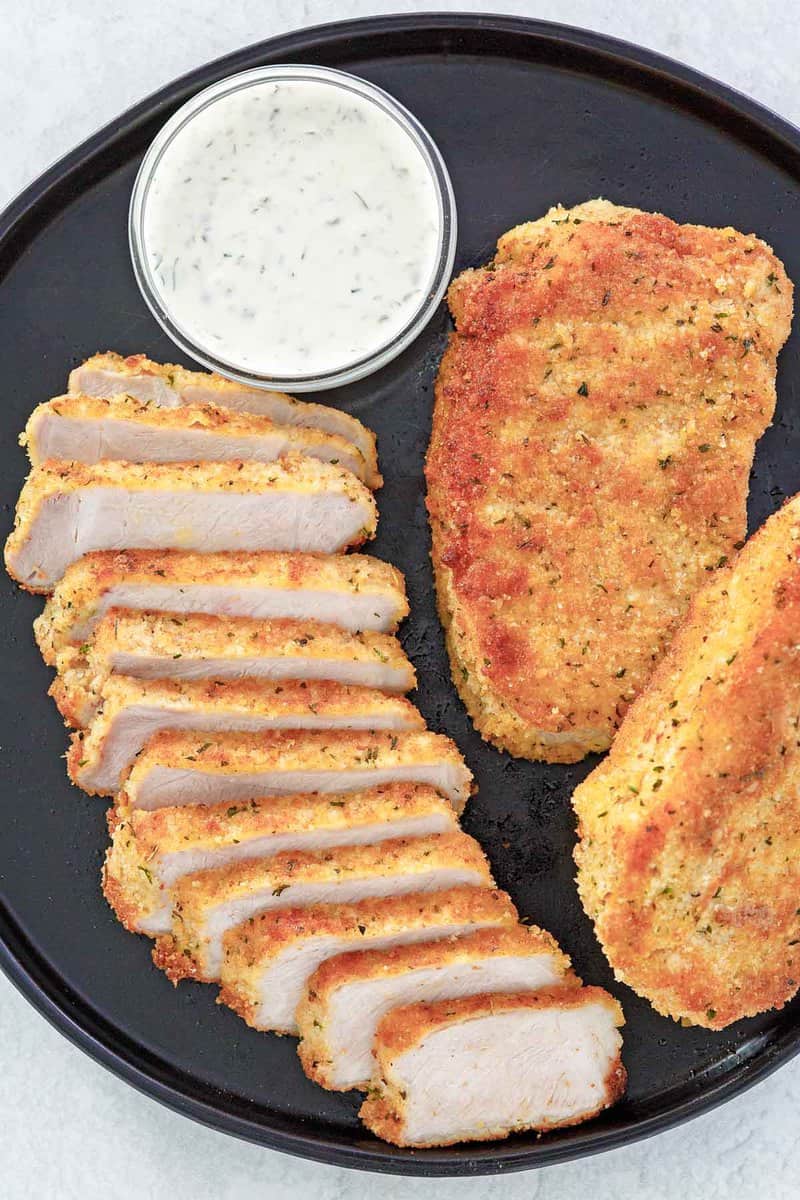 overhead view of pork milanese and lemon caper sauce on a platter.