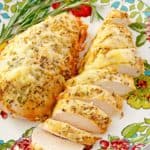 sliced and unsliced rosemary chicken breasts on a plate.