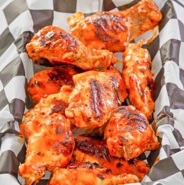 grilled buffalo chicken wings in a parchment paper lined basket.