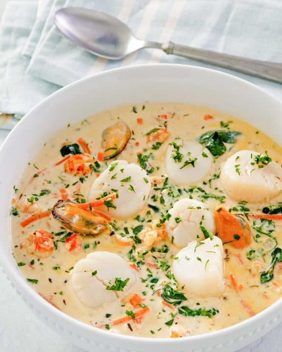 seafood bisque in a bowl and a spoon next to it.