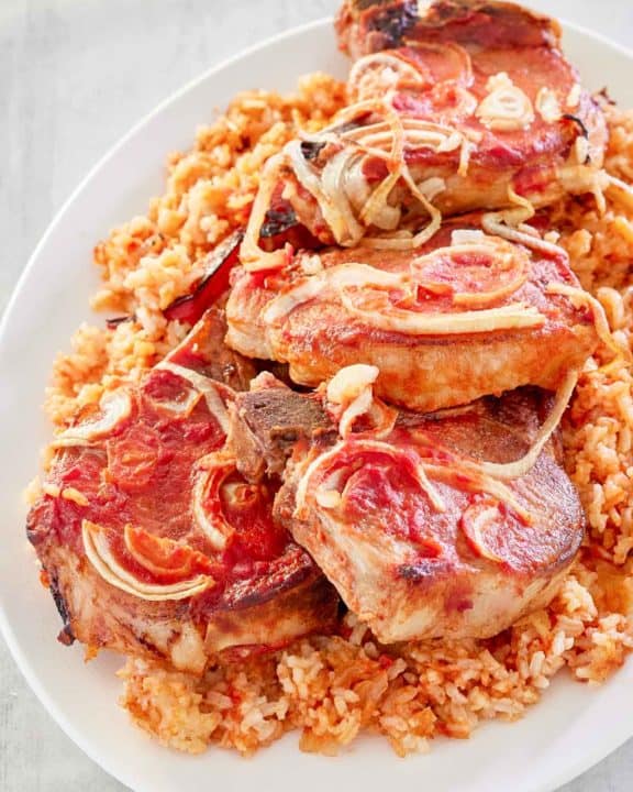 baked pork chops and rice on a white platter.