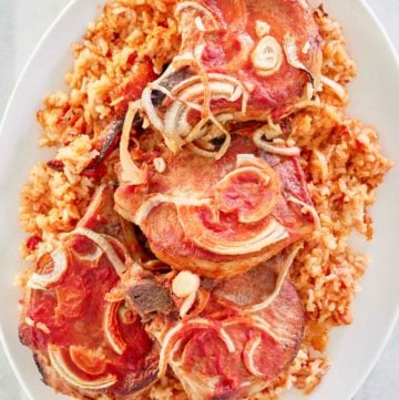 overhead view of baked pork chops and rice on a platter.