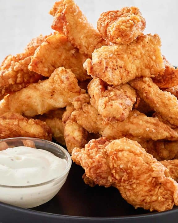beer battered chicken strips piled on a platter.