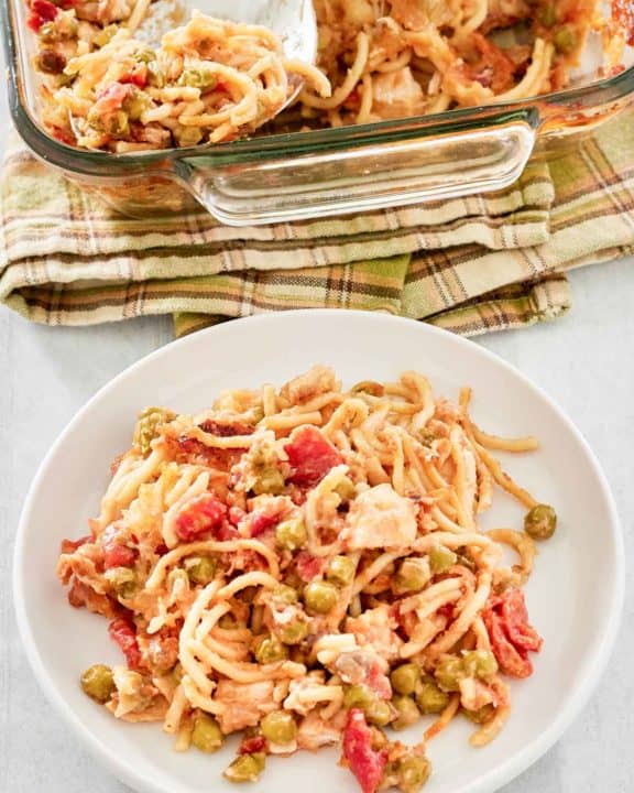 chicken spaghetti casserole on a plate and glass baking dish.
