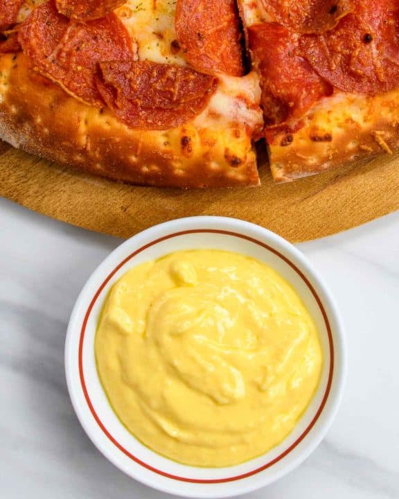 bowl of homemade Papa John's garlic sauce and a pizza.
