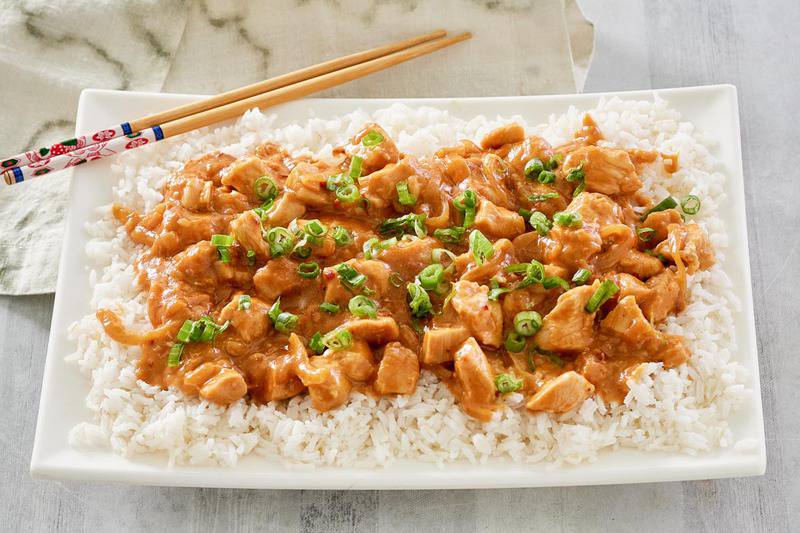Thai peanut chicken, rice, and chopsticks on a platter.