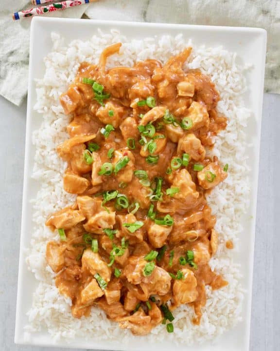 overhead view of Thai peanut chicken over rice on a platter.