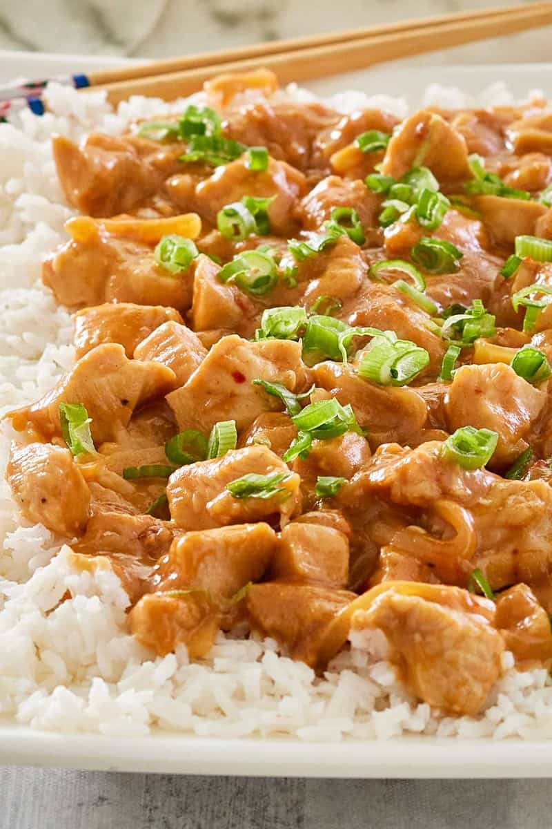 Thai peanut chicken over white rice on a platter.