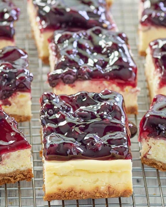blueberry cheesecake bars with graham cracker crust in a row.