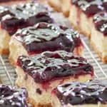 blueberry cheesecake bars in rows on a wire rack.