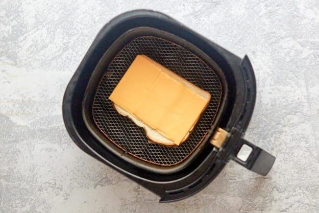 bread with cheese on top in an air fryer basket.