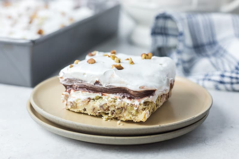 chocolate delight slice on a plate next to the dessert in a pan.
