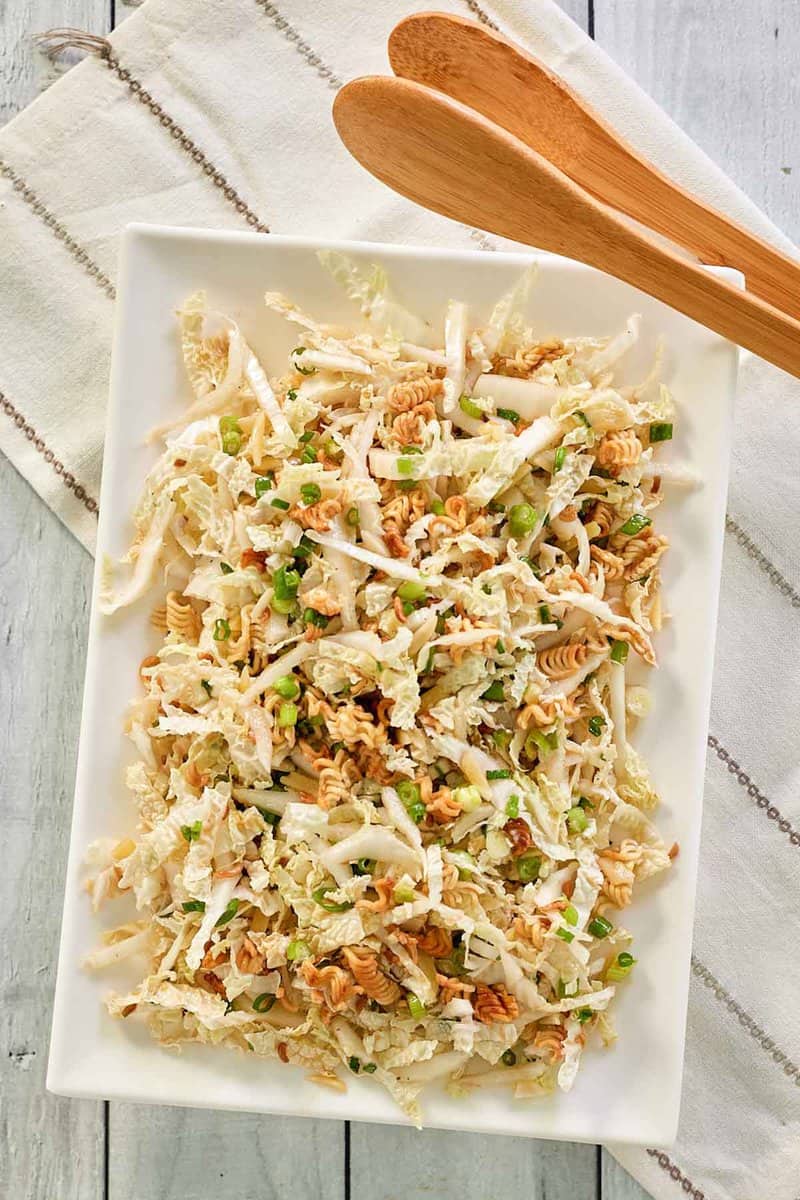 overhead view of Asian slaw on a platter and salad tongs.