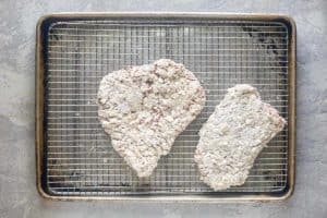 breaded cube steaks on a wire rack.