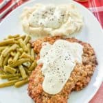 copycat Cracker Barrel country fried steak, gravy, and sides on a plate.
