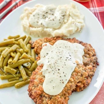 copycat Cracker Barrel country fried steak, gravy, and sides on a plate.