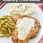 copycat Cracker Barrel country fried steak with gravy and sides on a plate.