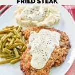 copycat cracker barrel country fried steak, gravy, and sides on a plate.