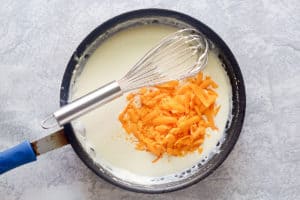 adding cheese to white sauce in a skillet.