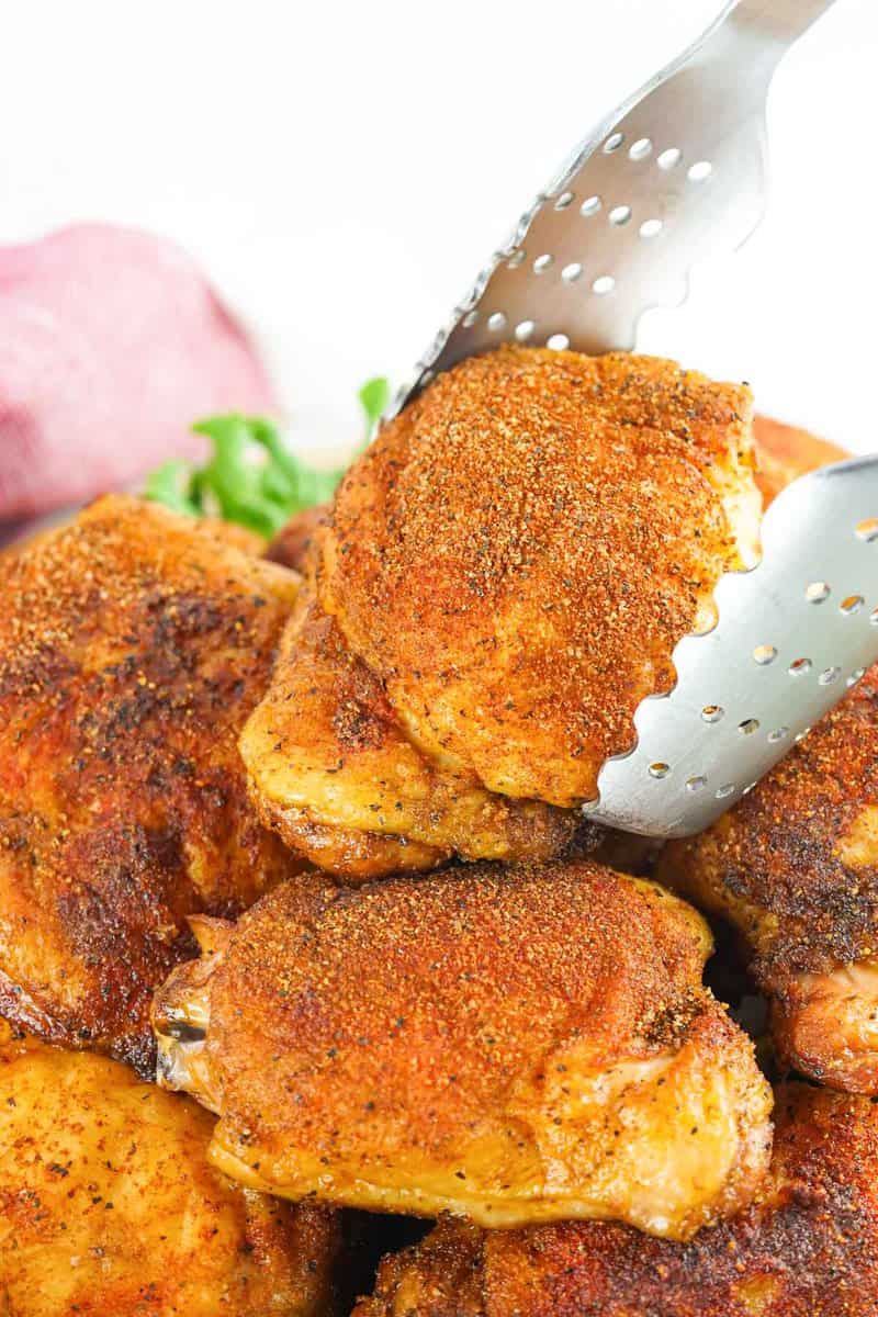 placing a smoked chicken thigh on top of more thighs.