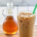 homemade Starbucks vanilla syrup in a small pitcher and an iced vanilla latte.