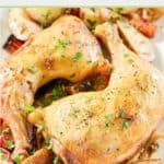 two baked chicken leg quarters and vegetables on a platter.