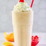 copycat Chick Fil A peach milkshake with whipped cream and a cherry.