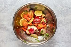 chopped vegetables, sliced lemons, and herbs in a bowl.