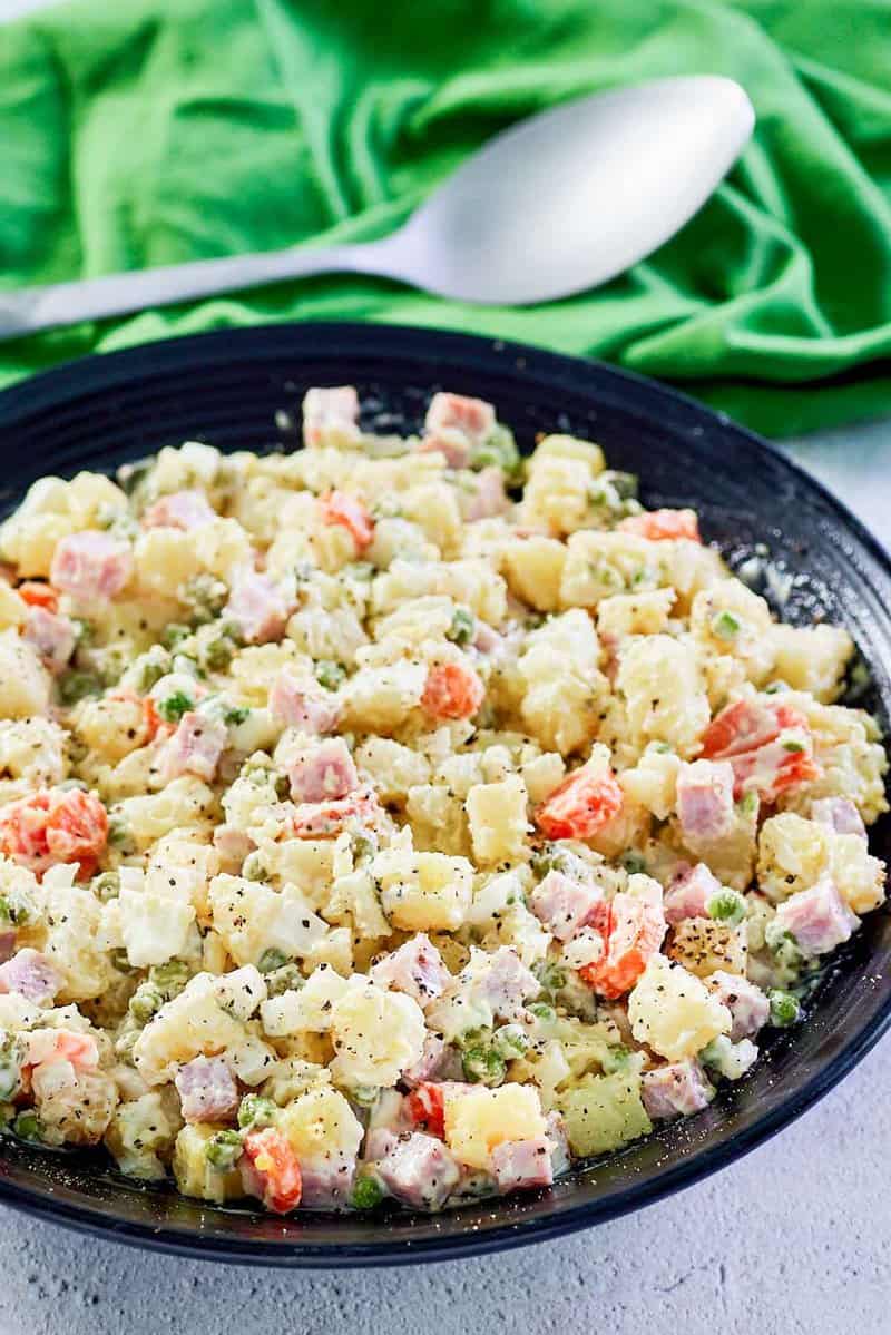 olivier salad in a bowl and a serving spoon behind it.
