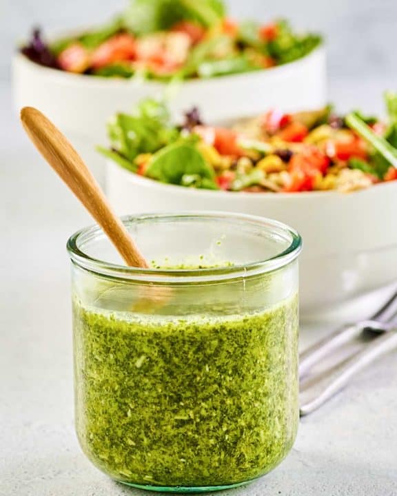 a jar of copycat Cheesecake Factory Santa Fe dressing in front of two salads.