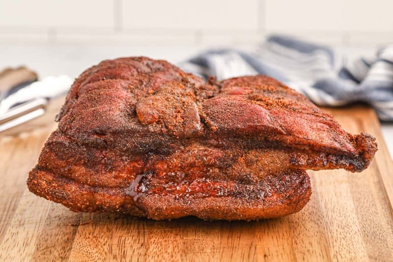 whole smoked pork belly on a wood board.