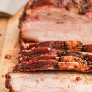 close up of smoked pork belly on a cutting board.
