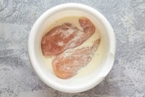 two chicken breasts marinating for a copycat Chick Fil A grilled chicken sandwich.