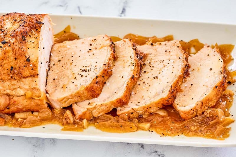 Instant Pot Pork Loin sliced and on top of onions on a platter.