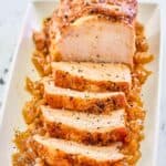Instant Pot pork loin on top of cooked onions on a platter.