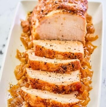 Instant Pot pork loin on top of cooked onions on a platter.