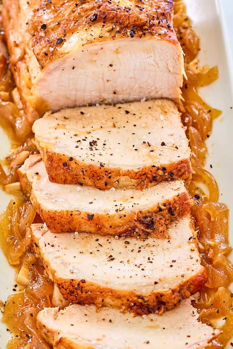 Instant Pot Pork Loin and cooked onions on a white platter.