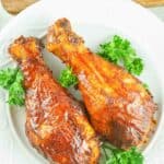 overhead view of two smoked chicken drumsticks on a plate.
