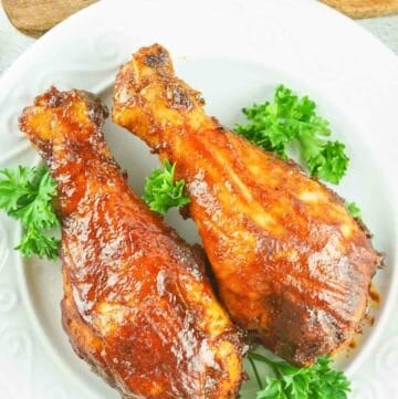 overhead view of two smoked chicken drumsticks on a plate.