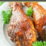 smoked barbecue chicken drumsticks and parsley on a white plate.