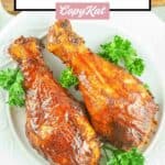 overhead view of two smoked barbecue chicken drumsticks on a plate.