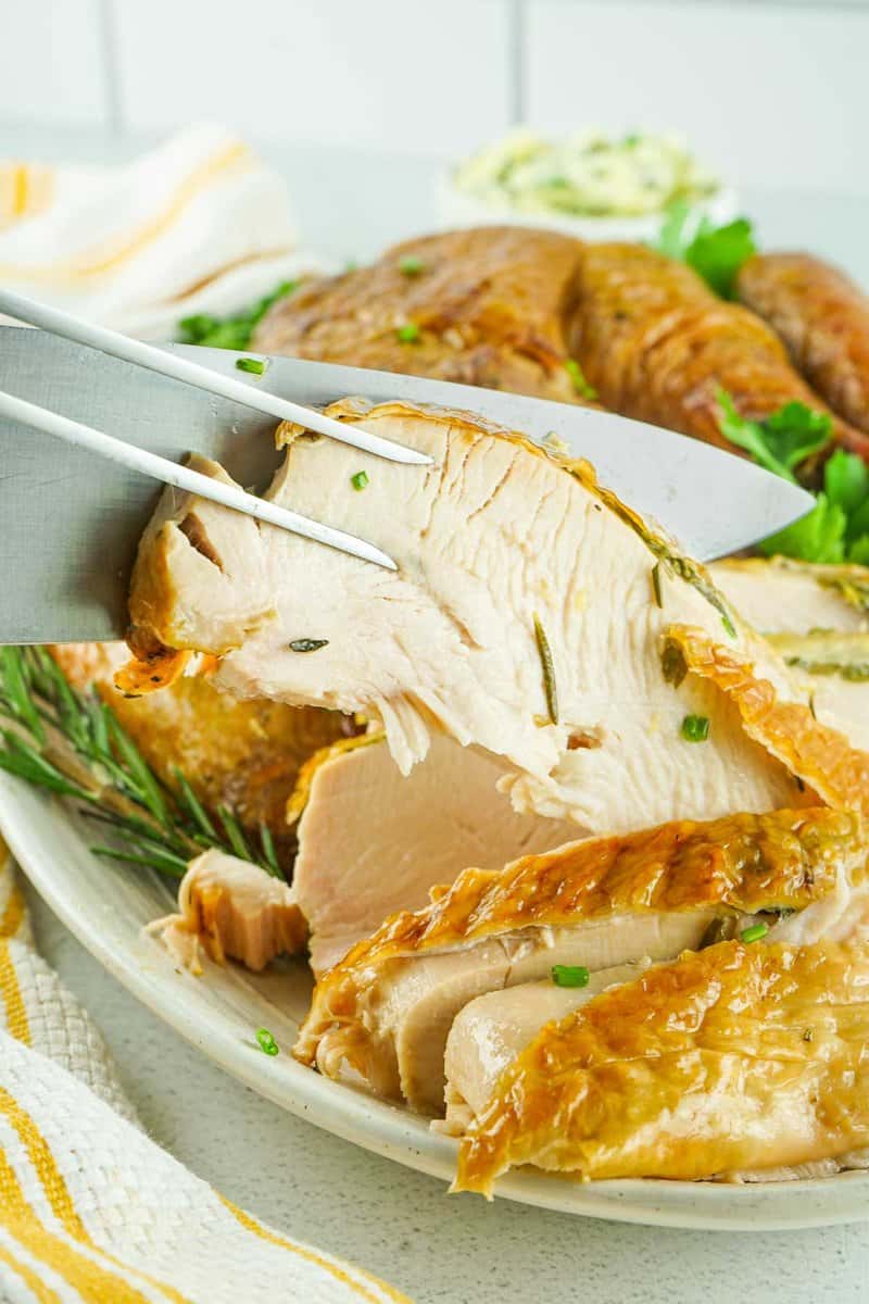 carving knife and fork holding a slice of smoked spatchcock turkey
