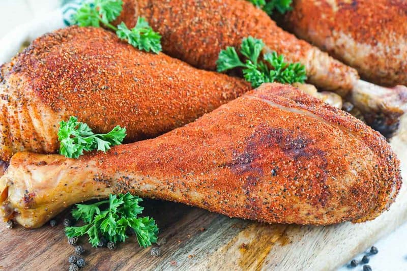 homemade smoked turkey legs on a wood serving board.