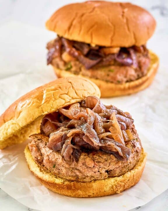 two turkey burgers with caramelized onions and whole grain buns.