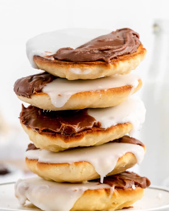 five black and white cookies in a stack on a plate.